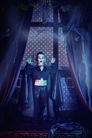 Halloween tales. Scary little boy in vampire costume is on Halloween night in the old castle.の写真素材