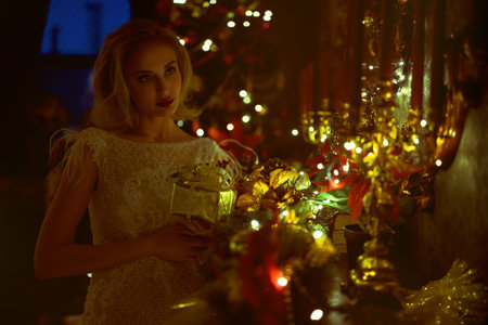 Christmas and New Year concept. Fashionable young woman wearing luxurious evening dress and with...