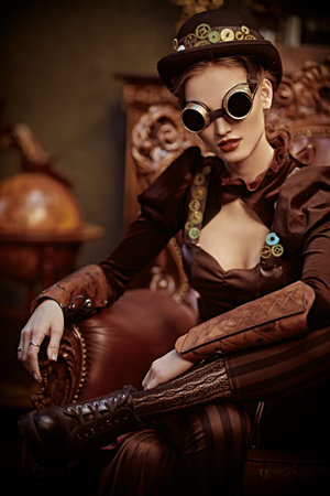 Beautiful steampunk woman sits in an armchair in a room with vintage victorian interior. Science...