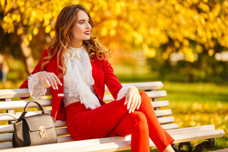 Charming young woman resting on a bench in a beautiful autumn park. Beauty, fashion.