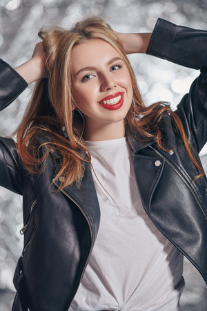 Portrait of a modern girl teenager in leather jacket and white t-shirt smiling at camera.