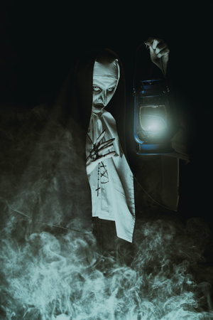 Scary cursed nun with lantern in hand emerges from the darkness. Horrors and Halloween.の写真素材