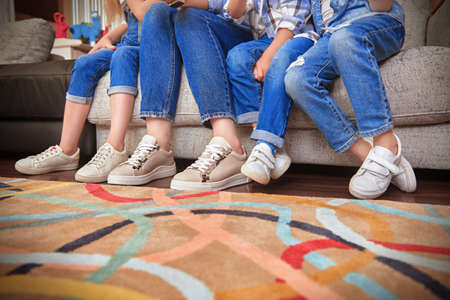 Family concept. Photo of four pairs of legs of children and their mother, sitting on the sofa in the living room.の写真素材