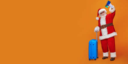 Santa Claus goes on vacation. Christmas Holidays, tourist trips to hot tropical countries. Bright yellow background. Copy space.の写真素材