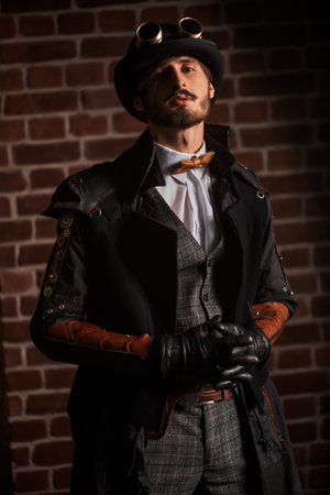 Steampunk world. Portrait of a stylish steampunk man in a coat and bowler hat on a brickwall...