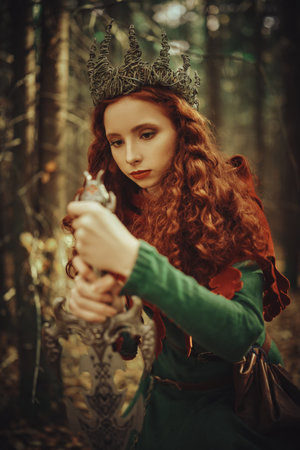 Ancient legends. A beautiful queen warrior woman with a sword in a deep forest. Fantasy world.
