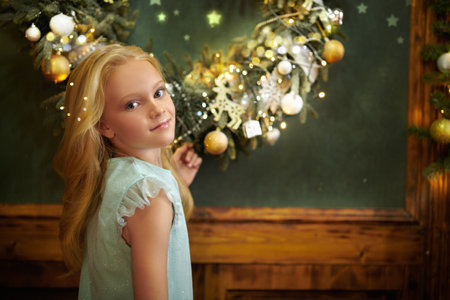 Portrait of a cute blonde girl standing in a house beautifully decorated for Christmas. Christmas and New Year.の写真素材