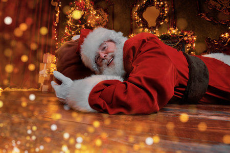 Jolly Santa Claus sneaked into the house through the fireplace with a bag of gifts. Beautiful home decoration. Merry Christmas and Happy New Year!の写真素材