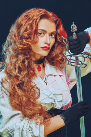 Portrait of a beautiful courageous woman with magnificent foxy hair holding her battle epee (rapier). Black backgroung.の写真素材