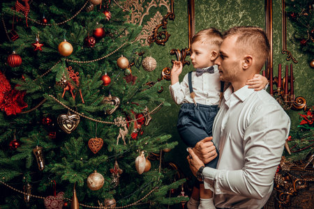 Family Christmas and New Year. Happy father shows his lovely little son a beautiful Christmas tree.の写真素材