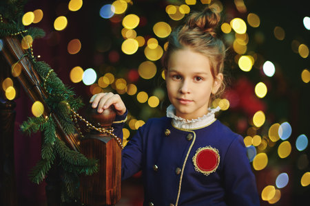 Portrait of a cute girl child in elegant classic school uniform standing on a festive background with glowing lights. Christmas and New Year.の写真素材