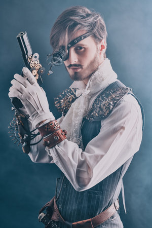 Steampunk man. Portrait of a handsome noble man with steampunk gadgets and a gun on a dark...