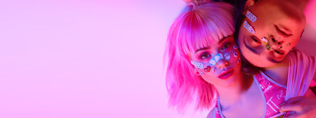 Youth beauty trends. Close-up portrait of a modern girl and a guy with bright dyed hair and bright makeup with stickers and decorative adhesive plaster on the face. Anime style. Copy space.の写真素材