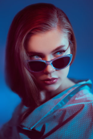 Portrait of a beautiful young woman in elegant glasses on a dark blue background. Glasses fashion.