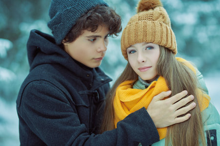 Couple of happy romantic young people teenagers hugging in a winter park and smiling. Winter season.の写真素材