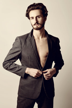 Men's fashion. Handsome brunet man fashion model poses in classic suit and with naked torso. Studio shot.の写真素材
