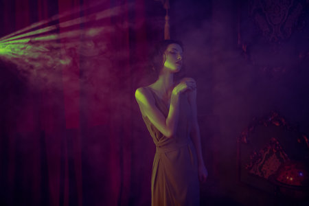 Portrait of a charming brunette girl in a dark room, illuminated by spotlights. Beauty, fashion. Art...