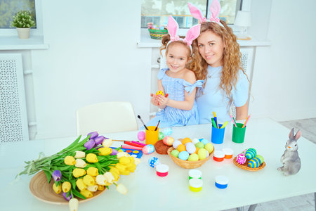 Loving family concept. Happy mother with her daughter with bunny ears are preparing for Easter....