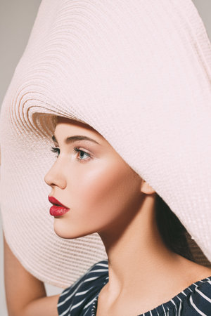 Side view portrait of a stunning young woman in elegant summer wide brim hat. Fashion shot, beauty.の写真素材