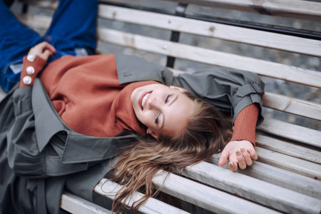 Happy beautiful girl lies with pleasure on a park bench. Happy day. Lifestyle.の写真素材