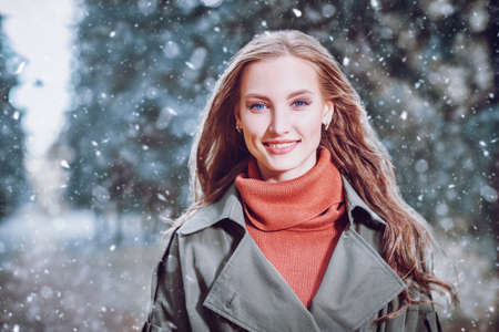 Portrait of a happy beautiful girl in a winter park under the snow. Happy winter day.の写真素材