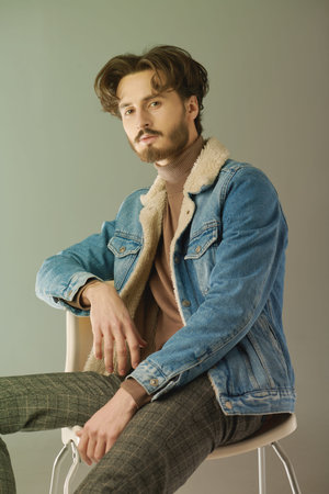 Men's fashion. Portrait of a handsome brunet man posing at studio in trendy casual clothes. Denim style.の写真素材