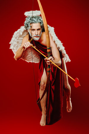 An angel who makes people fall in love. Full length portrait of a Cupid flying with the bow and...