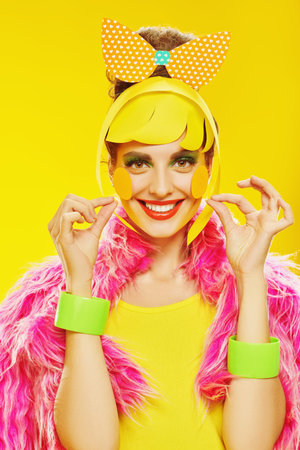 Happy glamorous girl with colorful paper makeup and hairstyle poses in fashionable vivid clothes on...