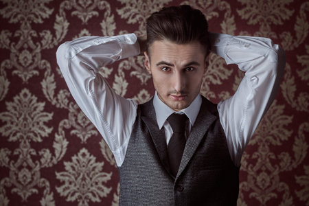 Portrait of a handsome man in elegant classic suit and a tie on a vintage background. Business...