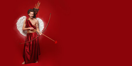 Full length portrait of a Cupid with the bow and arrow of love on a red background. Copy space....