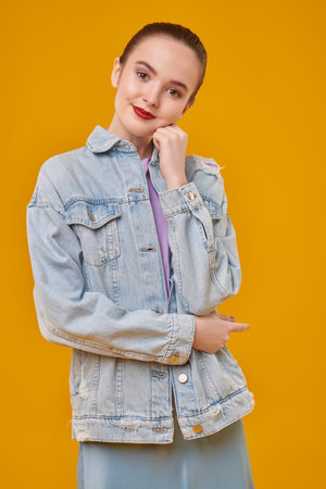Portrait of a pretty teenager girl with natural makeup and red lips on a yellow background. Beauty,...