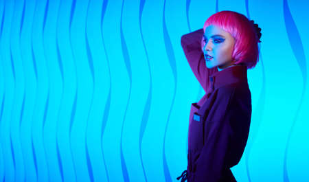 Fashion beauty trends. Portrait of a gorgeous young woman with bright glitter makeup and pink hair posing in mixed color neon light. Makeup cosmetics and hairstyle. Copy space.の写真素材