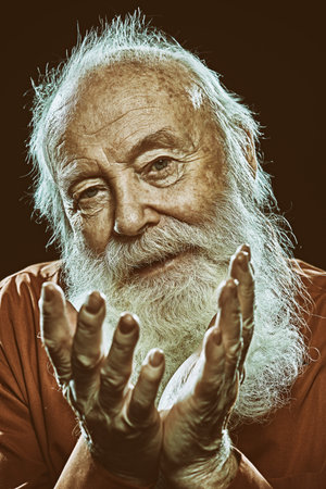 Portrait of an old gray-haired man looking at camera. Black background. Old age concept.