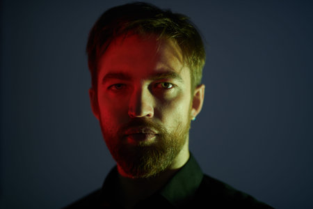 Portrait of a handsome middle aged man in black shirt in a mixed light in dark. Men's beauty.