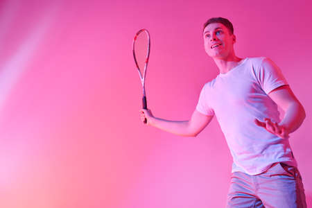 Excited sporty man playing squash with pleasure. Active lifestyle. Sports and healthcare. Studio portrait. Copy space.の写真素材