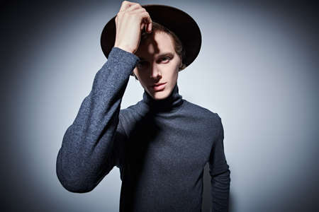 Portrait of an artistic young man in a wide-brimmed hat to the camera. Studio portait.の写真素材