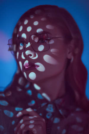 Portrait of a beautiful young woman in elegant glasses in light and shadow. Glasses fashion. Business style.の写真素材