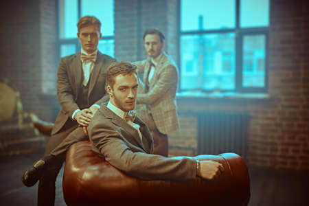 Three handsome men in elegant are posing in apartments with loft interior. Business people club. Men's fashion.の写真素材