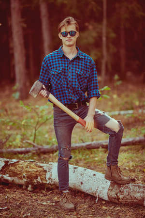 Full length portrait of a handsome strong man lumberjack with an ax in the wild forest. Work in nature.の写真素材