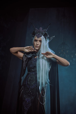 Stately and beautiful old woman with long gray hair, in a rich headdress and black dress against a...