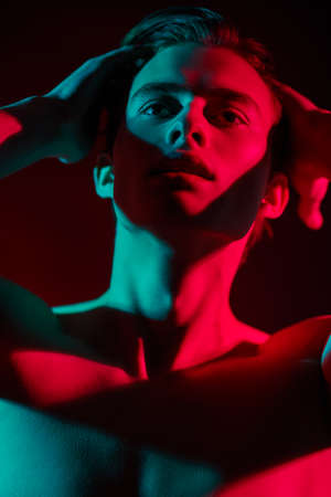 Close up portrait of a emotional young man shirtless in multicolored lights. Man's beauty and health. Art portrait.の写真素材