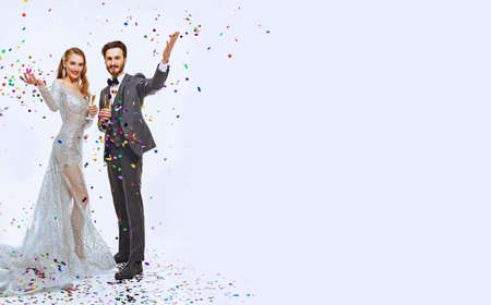 Full length portrait of a gorgeous woman and handsome man in luxury evening dresses on a white background with confetti. Fashion and holidays. Christmas and New Year celebration.の写真素材