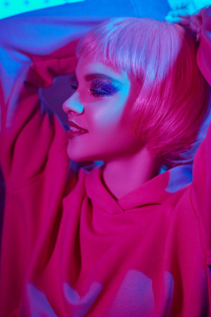 Close-up portrtait of a happy fashion model girl with bright glitter make-up in mixed color neon...