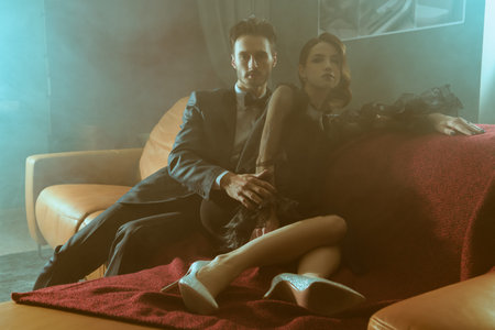 Beautiful elegant couple in fashionable evening clothes posing in haze in luxury apartment....