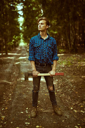 Full length portrait of a handsome strong man lumberjack with an ax in the wild forest.の写真素材