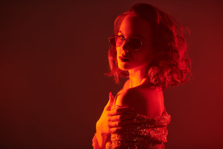 Attractive girl in sparkling top and stylish glasses alluring in red light in the smoke. Night...
