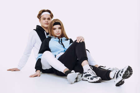 Couple of modern teenagers a boy and a girl pose together in fashionable sportswear at studio. Sport style.の写真素材