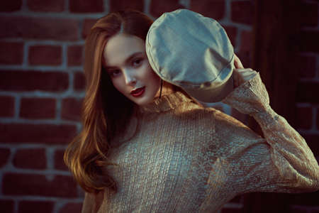 Portrait of a romantic young girl with natural make-up and in a light beige dress posing with cap. Beauty, fashion concept.の写真素材