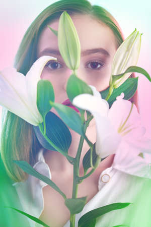 Beautiful young tender girl with lily flowers in a light pink-blue haze. Inspiration of spring and summer. Perfume, cosmetics concept.の写真素材