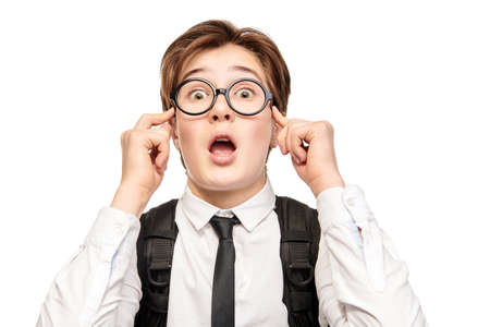 Surprised student boy. School and education. Portrait of an emotional smart teen boy in school uniform and glasses. Studio portrait on a white background with copy space.の写真素材